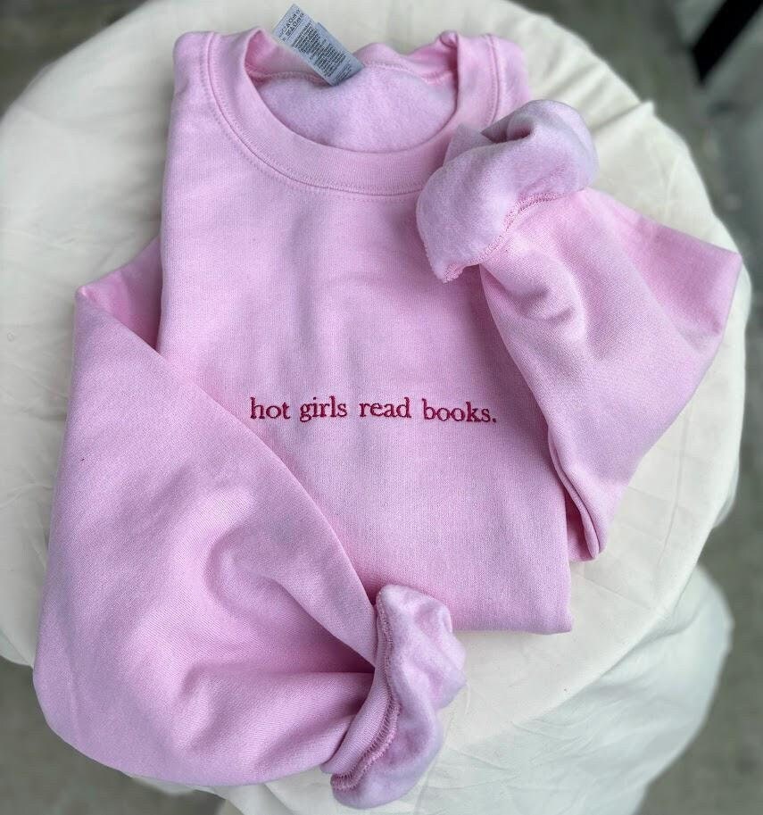 Embroidered sweatshirt with the phrase &quot;Hot Girls Read Books&quot; in stylish script. Cozy and chic, this sweatshirt celebrates book lovers with a bold statement. Perfect for bibliophiles who embrace both style and intellect. In various colors and sizes.