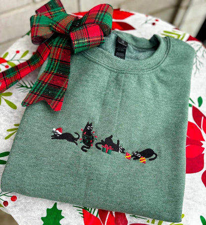 Embroidered green sweatshirt featuring four playful cats with Christmas gifts and holiday lights wrapped around them, perfect for a cozy, festive look.